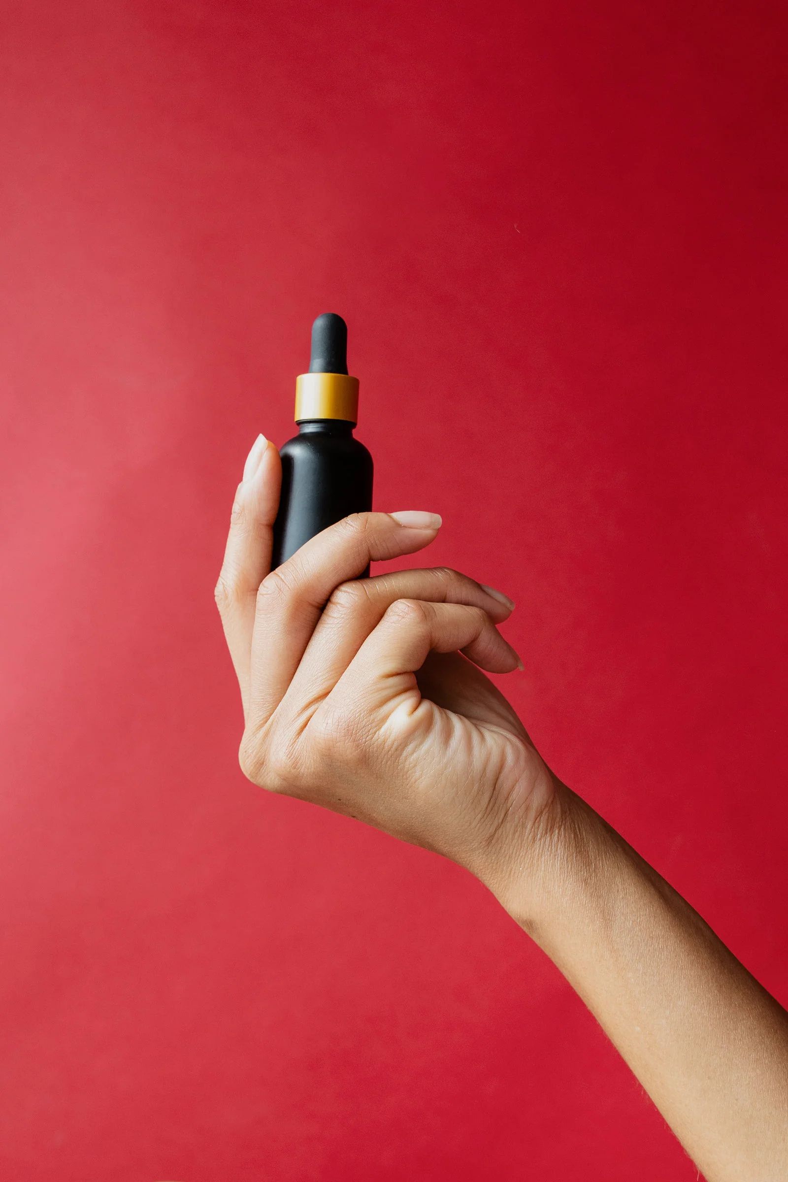 A hand holding a dropper bottle