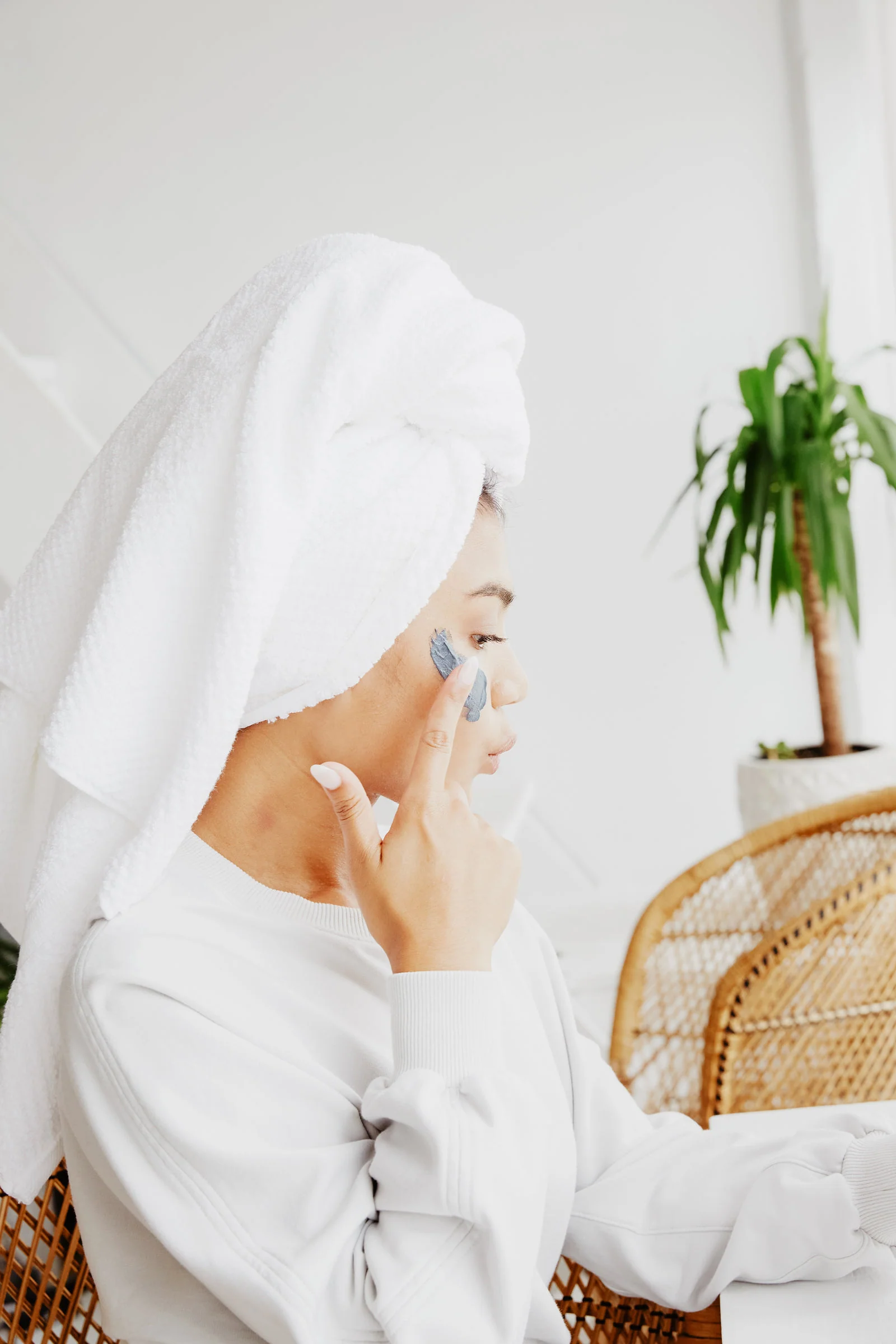 A person in a towel applying a face mask