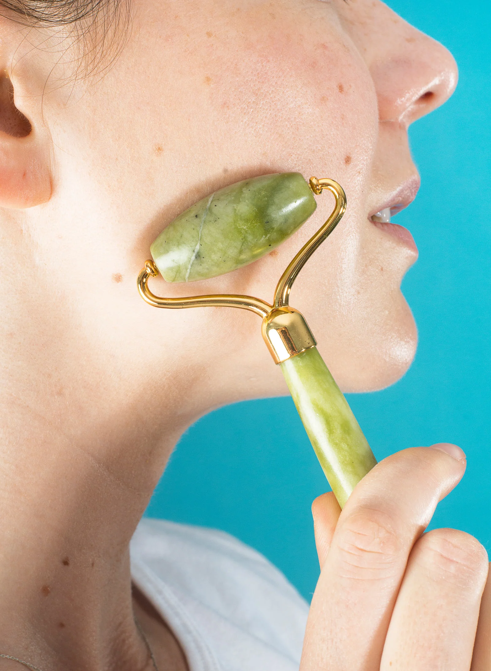 A jade roller on a cheek