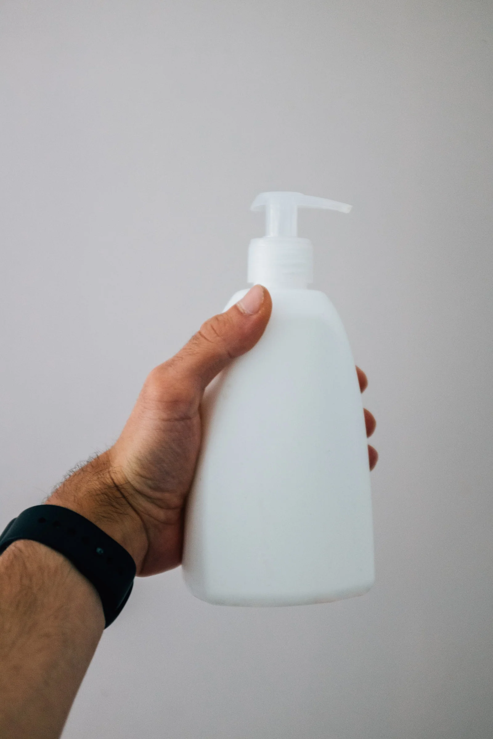 A hand holding a white pump bottle